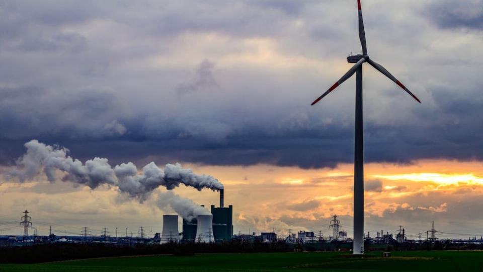 Eine Windmühle vor einem Kohlekraftwerk