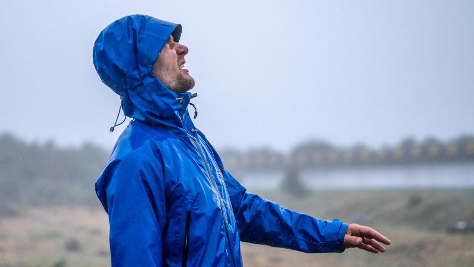 Man in a waterproof coat looking up at the sky