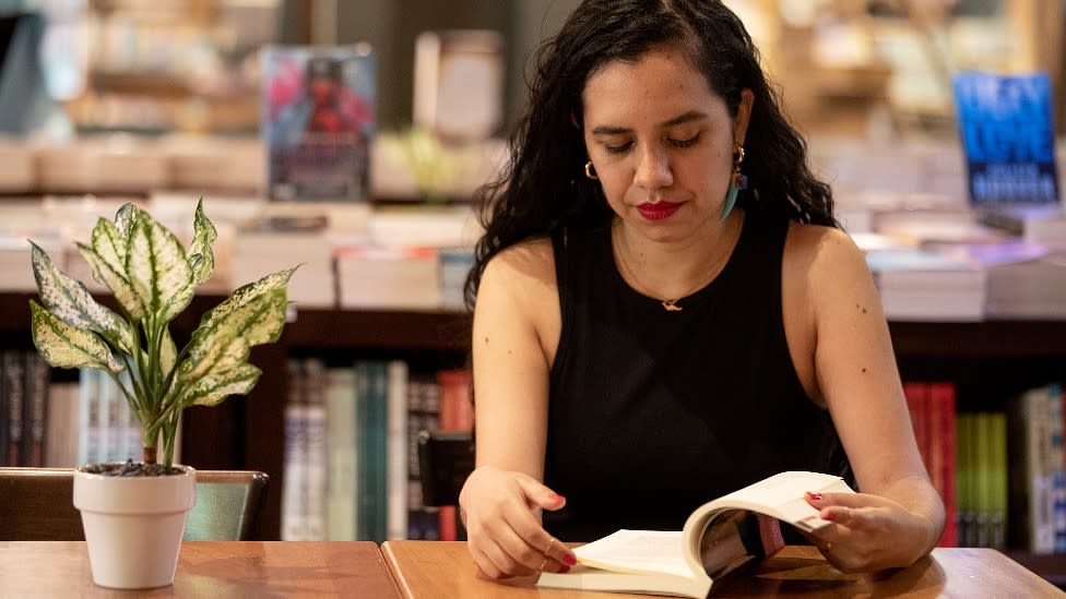 Astrid Morales viendo un libro en una librería