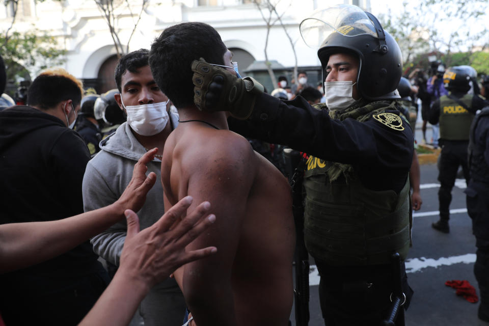 A police officer places a protective face mask on a protester who was detained near Congress where lawmakers swore-in a new president after voting to oust President Martin Vizcarra the day before, in Lima, Peru, Tuesday, Nov. 10, 2020. Peru swore in businessman and head of Congress Manuel Merino Tuesday who is unknown to most and was recently accused of trying to secure the military’s support for a congressional effort to boot the nation’s last leader out over unproven corruption allegations. (AP Photo/Rodrigo Abd)