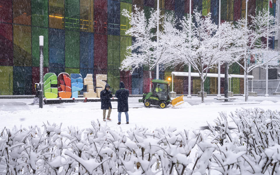 Delegates take souvenir photos during a snowfall outside the convention centre at the COP15 UN conference on biodiversity in Montreal, Friday, Dec. 16, 2022. (Paul Chiasson /The Canadian Press via AP)