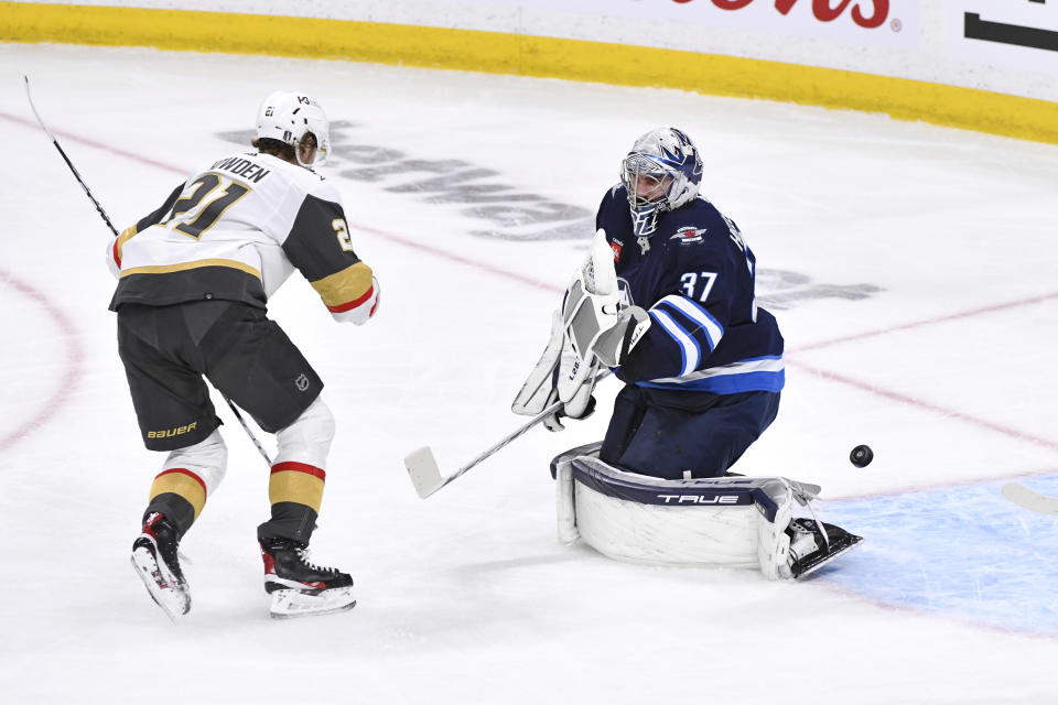 Vegas Golden Knights' Brett Howden (21) scores against Winnipeg Jets' goaltender Connor Hellebuyck (37) during first-period Game 4 NHL Stanley Cup first-round hockey playoff action in Winnipeg, Manitoba, Monday April 24, 2023. (Fred Greenslade/The Canadian Press via AP)