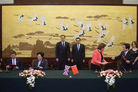 Britain's Prime Minister David Cameron (rear L) and China's Premier Li Keqiang (rear R) watch a signing ceremony at the Great Hall of the People in Beijing December 2, 2013. REUTERS/Ed Jones/Pool