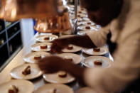 A chef dresses plates for diners at Brasserie Surrealiste in Brussels, Wednesday, Sept. 28, 2022. A group of restaurant owners in Brussels has imagined how a future without gas and electricity would look like for gourmets. Dinner guests, served at the Brasserie Surrealiste and cooked by Racines restaurant employees, were the first to experience it: No ovens, no stoves, no hot plates, no coffee machines and no light bulbs. (AP Photo/Olivier Matthys)