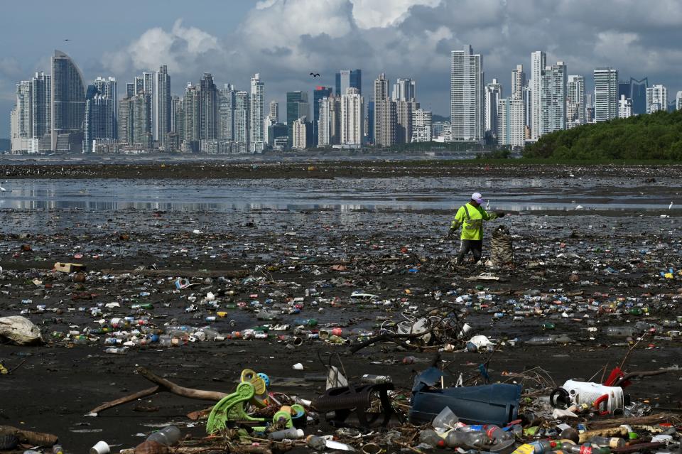 A man collects garbage, including plastic waste, at the beach of Costa del Este, in Panama City, on April 19, 2021. (Luis Acosta/AFP via Getty Images)