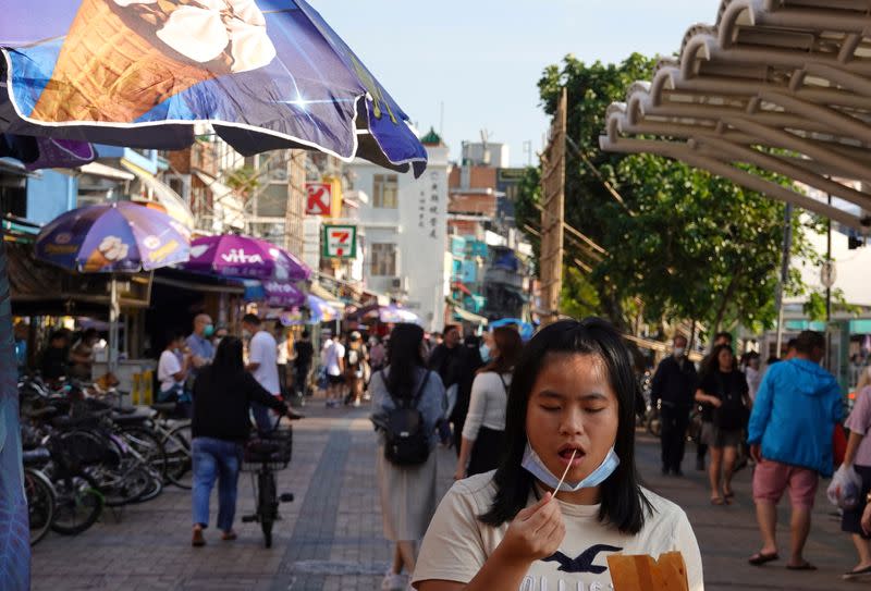 A woman takes off her mask as she eats food during Easter weekend at Cheung Chau island, amid the novel coronavirus disease (COVID-19) outbreak, in Hong Kong