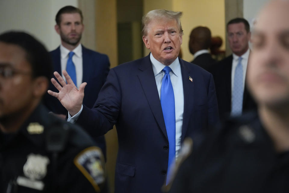 Former President Donald Trump, in a blue suit with a blue tie, speaks to reporters. 