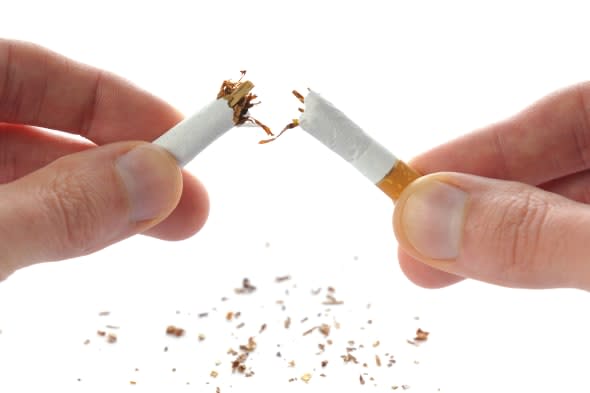 'Quit smoking, cigarette in hands broken in half, isolated on white.'