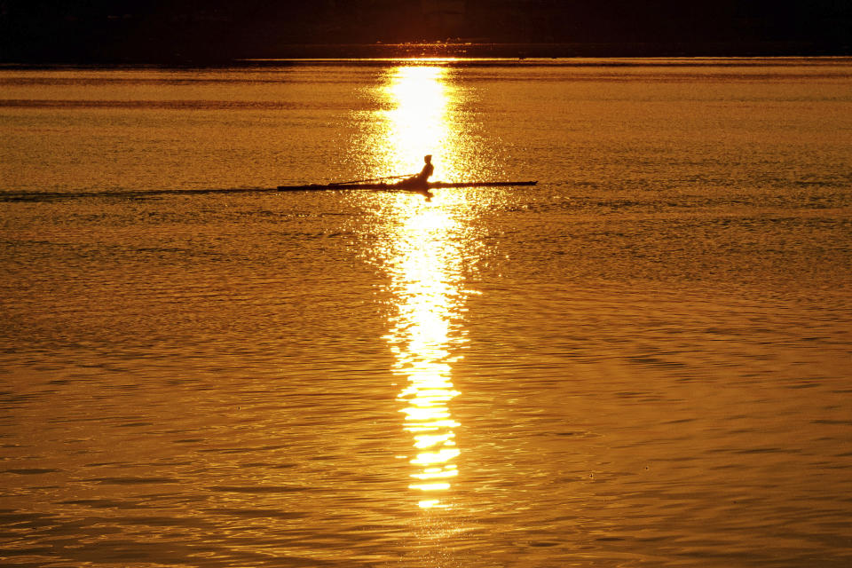 An early morning rower glides through the glare of the rising sun on the Potomac River at the start of a hot day in Washington, Saturday July 20, 2019. Temperatures in the Nation's Capital are expected to reach the upper 90s. (AP Photo/J.David Ake)
