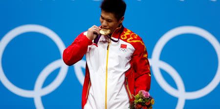 China's Xiaojun Lu bites his gold medal at the podium of the men's 77Kg weightlifting competition at the ExCel venue at the London 2012 Olympic Games August 1, 2012. REUTERS/Grigory Dukor