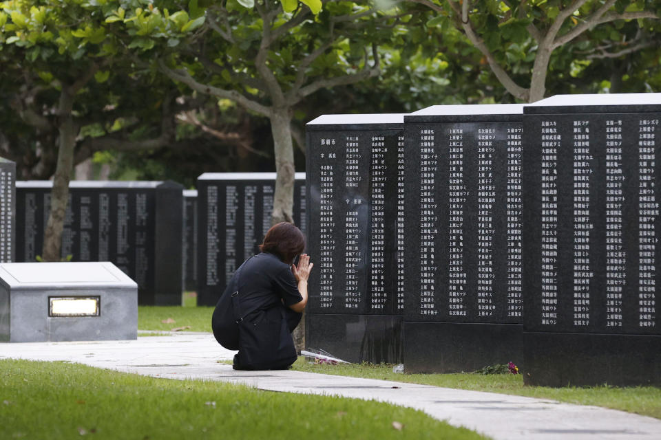 A woman prays in front of a "Cornerstone of Peace" monument wall on which the names of all those who lost their lives, both civilians and military of all nationalities in the Battle of Okinawa are engraved, at the Peace Memorial Park in Itoman, Okinawa, Japan, Tuesday, June 23, 2020. Okinawan people find it unacceptable that their land is still occupied by a heavy U.S. military presence even 75 years after World War II. They have asked the central government to do more to reduce their burden, and Prime Minister Shinzo Abe's government repeatedly say it is mindful of their feelings, but the changes are slow to come. (Kyodo News via AP)