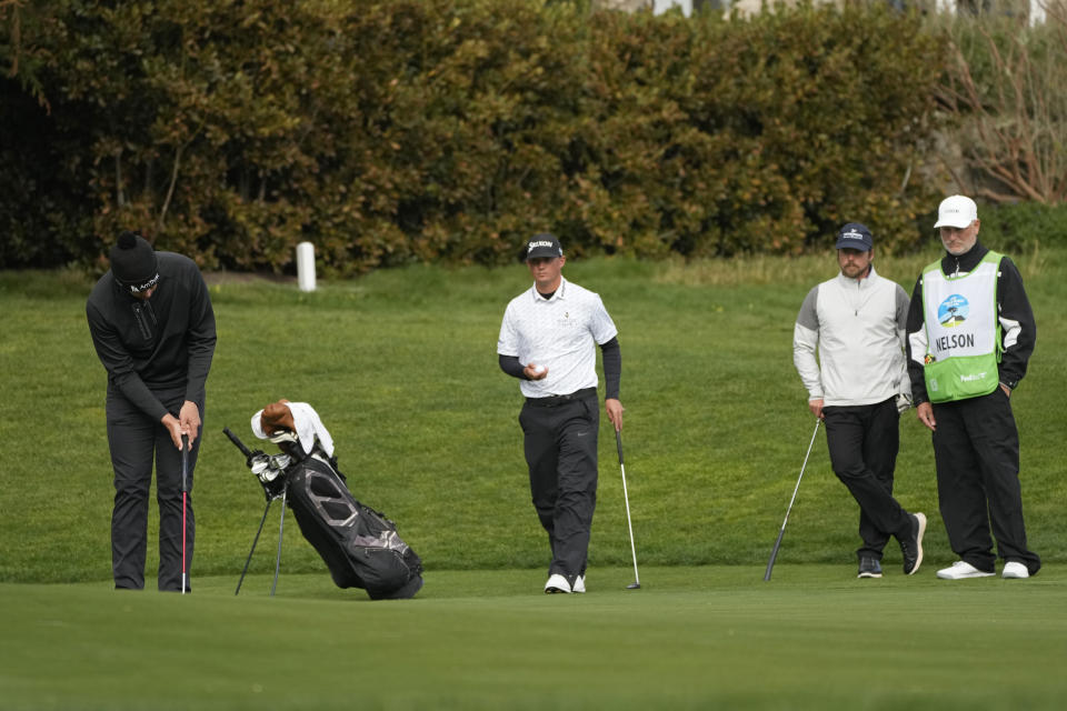 Beau Hossler, left, putts on the 13th green of the Pebble Beach Golf Links as Max McGreevy, center, and Lukas Nelson, second from right, look on during the second round of the AT&T Pebble Beach Pro-Am golf tournament in Pebble Beach, Calif., Friday, Feb. 3, 2023. A caddie for one of the amateurs in the group collapsed on the 11th fairway and was rushed to the hospital. (AP Photo/Eric Risberg)