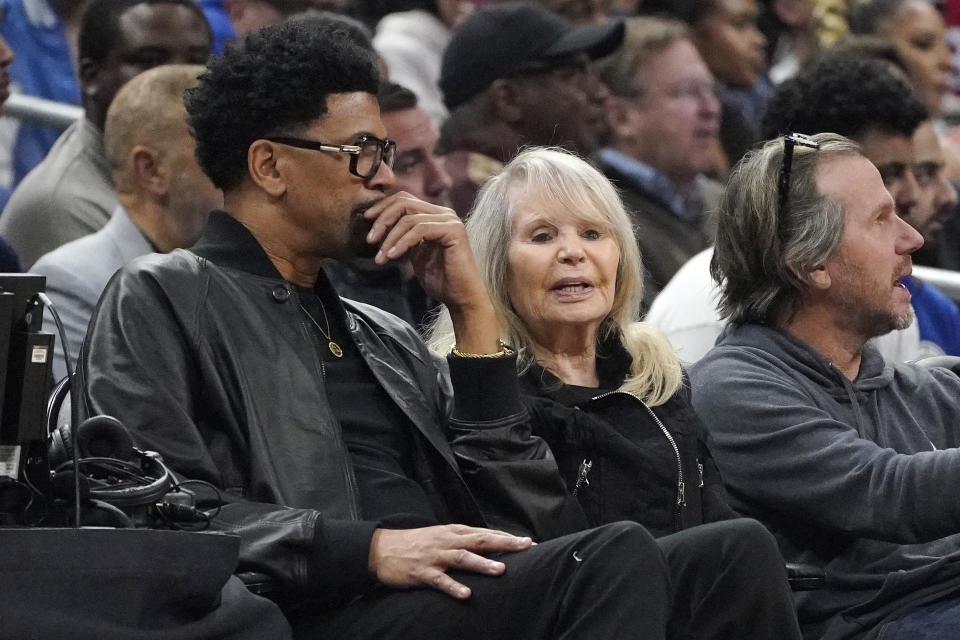 Shelly Sterling, center, sits with Jalen Rose, left, during the first half of an NBA basketball game between the Los Angeles Clippers and the Dallas Mavericks Wednesday, Feb. 8, 2023, in Los Angeles. (AP Photo/Mark J. Terrill)