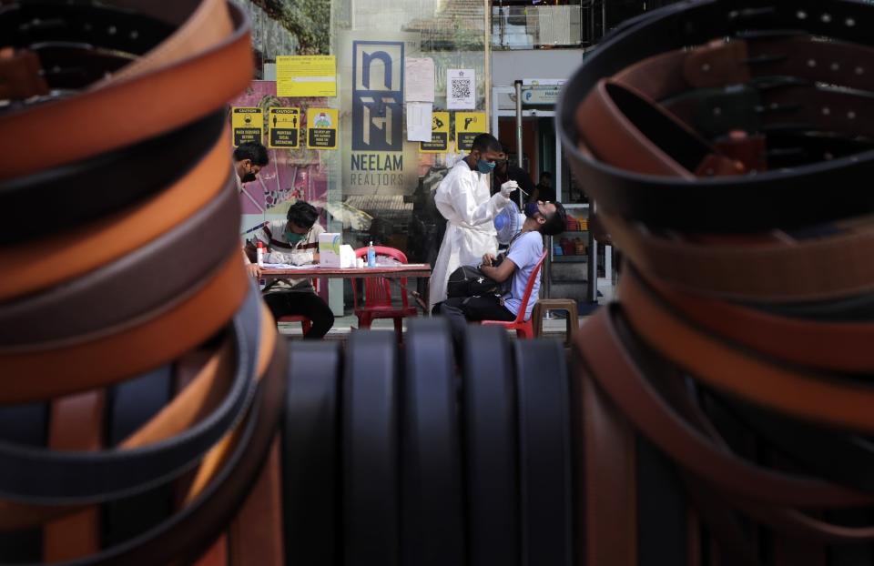 A health worker takes a swab sample to test for COVID-19 outside shopping mall in Mumbai, India, Saturday, April 3, 2021. (AP Photo/Rajanish Kakade)