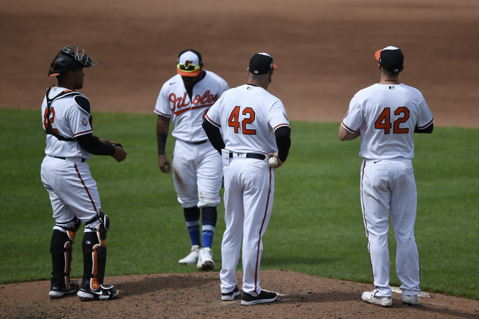 Baltimore Orioles manager Brandon Hyde, center right, stands on the pitching mound during a pitching change in the sixth inning of the first baseball game of a doubleheader against the Seattle Mariners, Thursday, April 15, 2021, in Baltimore. (AP Photo/Gail Burton)