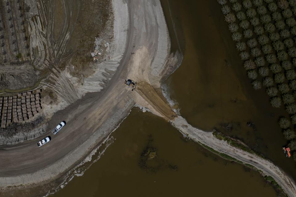 Heavy equipment reinforces levees in preparation of possible flooding as farmland in the Tulare Lake Basin is submerged in water in Corcoran, Calif., Thursday, April 20, 2023