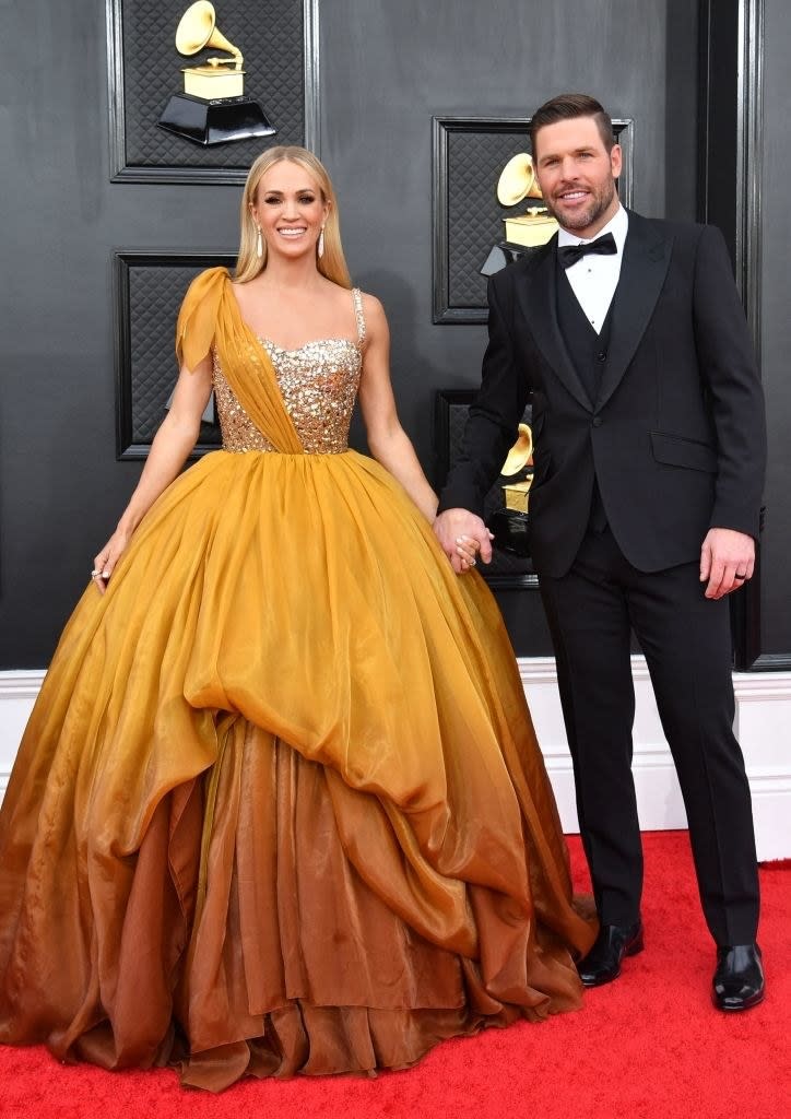 Smiling Carrie in a long princess gown and holding hands with John, who's wearing a bow tie