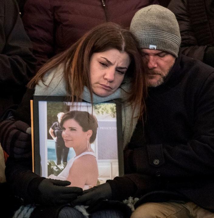 Rana Abbas Taylor holds a photo of her sister Rima Abbas while being comforted by her husband Tom during a candlelight vigil for the Abbas family at the Ford Field Park in Northville on Jan. 11, 2019.