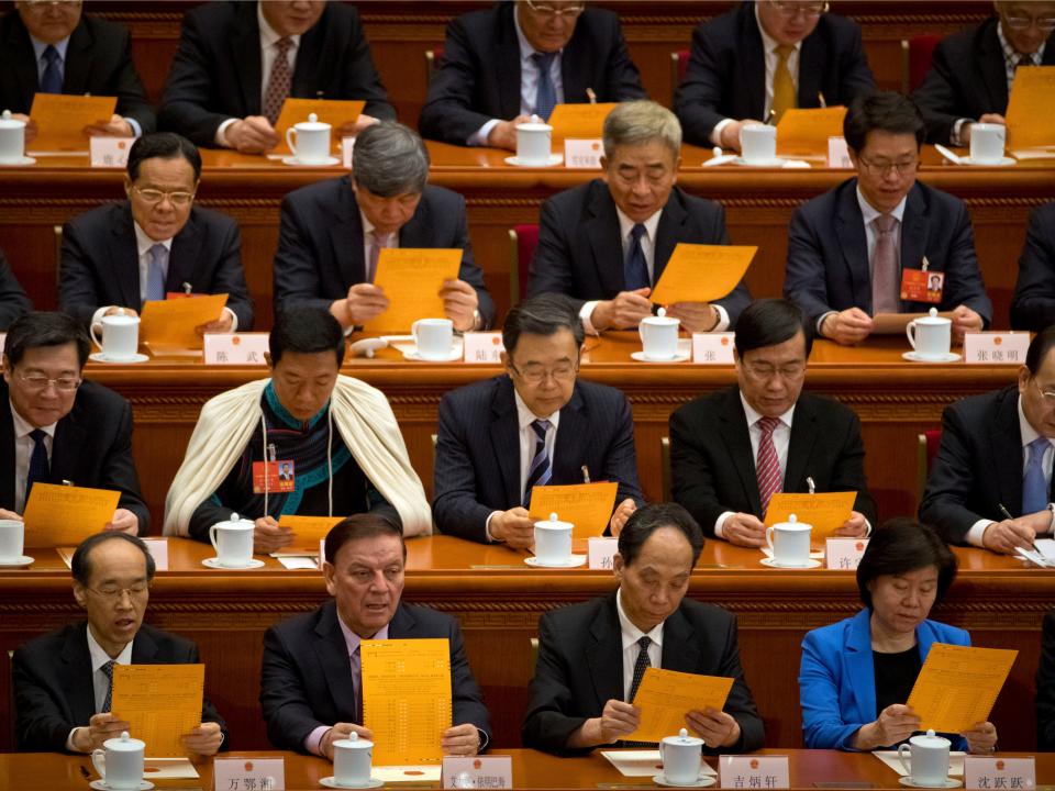 FILE - In this March 19, 2018, file photo, delegates look at their ballots during a plenary session of China's National People's Congress (NPC) at the Great Hall of the People in Beijing. In an unusual step, China’s ceremonial legislature is due to endorse a law meant to help end a bruising tariff war with Washington by discouraging officials from pressuring foreign companies to hand over technology. (AP Photo/Mark Schiefelbein, File)