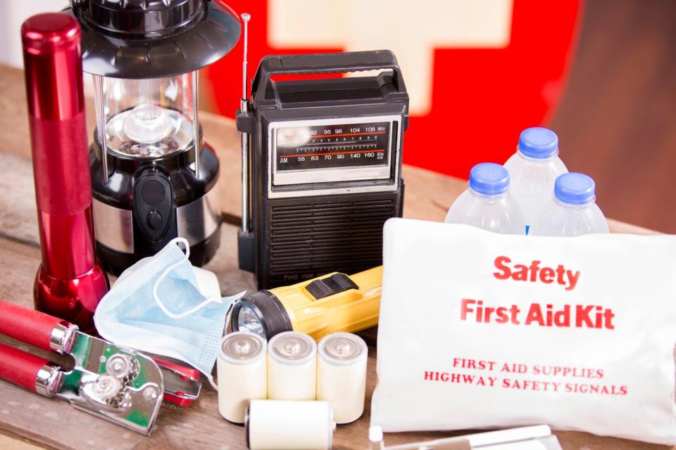 Emergency preparedness supplies including water, a lamp, a can opener, and a first aid kit.
