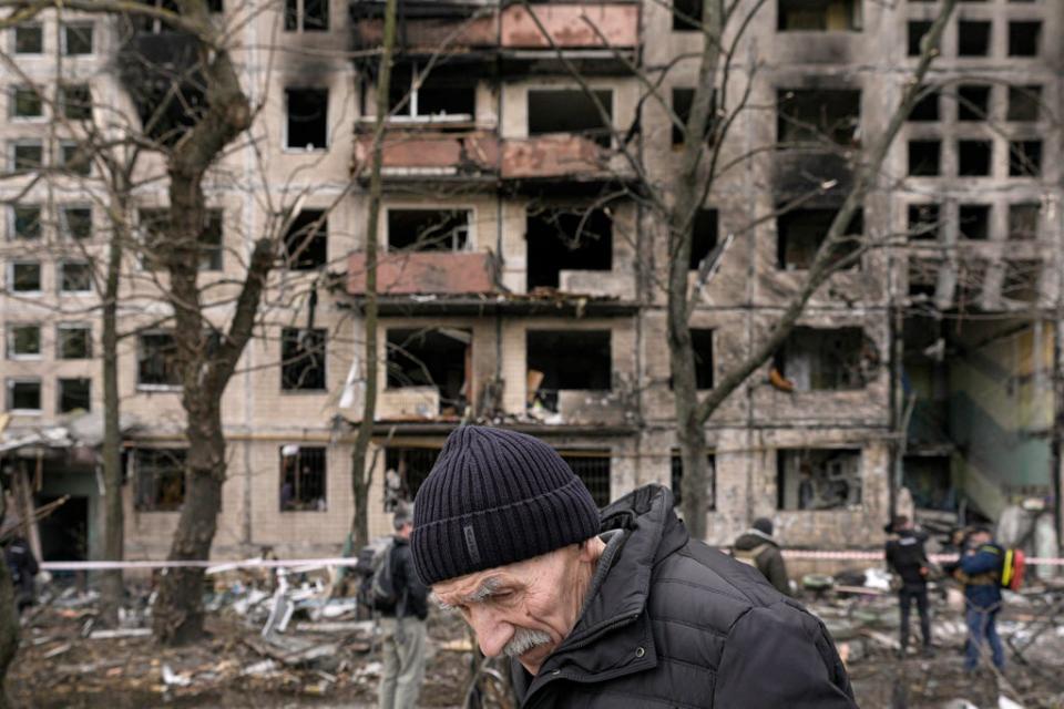 An elderly man walks outside an apartment block which was destroyed by an artillery strike in Kyiv on 14 March (AP)