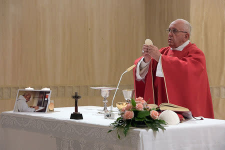 Pope Francis holds up the Host on the altar next to a picture of Father Jacques Hamel during a mass in his memory at the Vatican, September 14, 2016. Osservatore Romano/Handout via REUTERS