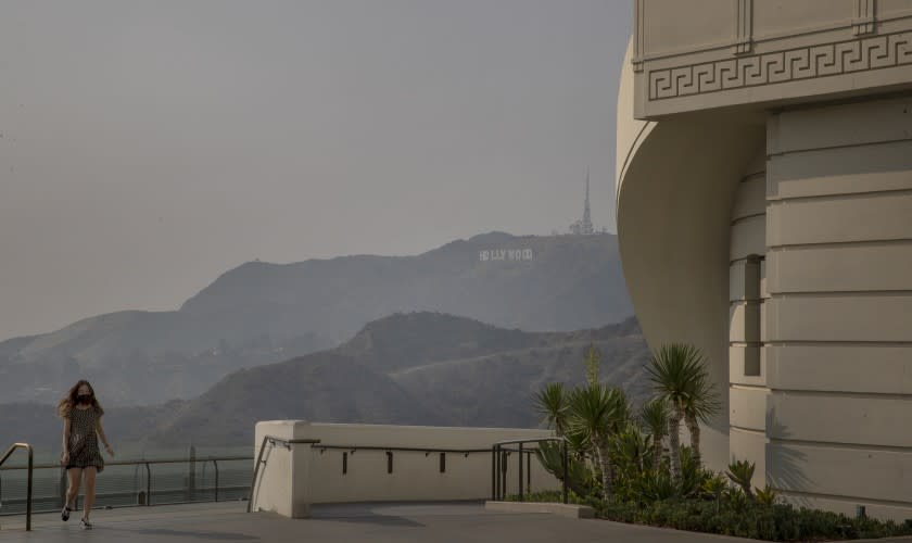 LOS ANGELES, CA - SEPTEMBER 14: A visitor walks around the Griffith Observatory with a smokey/smoggy view of the Los Angeles skyline and Hollywood sign Monday, Sept. 14, 2020 in Los Angeles. Wildfires are choking California's skies with smoke, littering cities with ash, creating dangerous levels in regional air quality and transforming the sun at times into an ominous red orb. (Allen J. Schaben / Los Angeles Times)