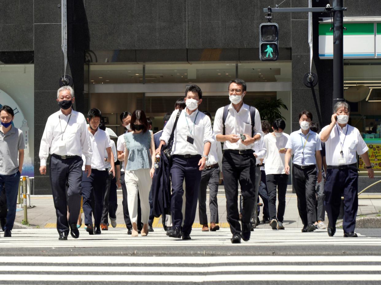 People wearing face masks to help curb the spread of the coronavirus walk past a crossing in busy Shinjuku district in Tokyo Friday, Aug. 6, 2021.