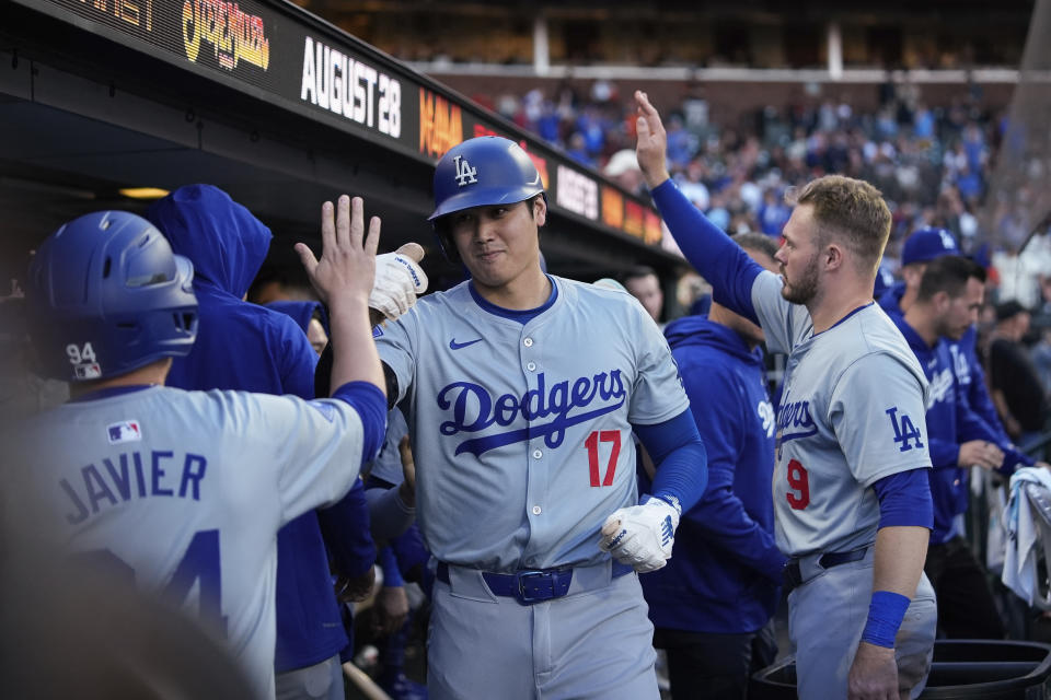 Los Angeles Dodgers' Shohei Ohtani, center, celebrates with teammates in the dugout after scoring against the San Francisco Giants on Will Smith's double during the 11th inning of a baseball game Saturday, June 29, 2024, in San Francisco. (AP Photo/Godofredo A. Vásquez)