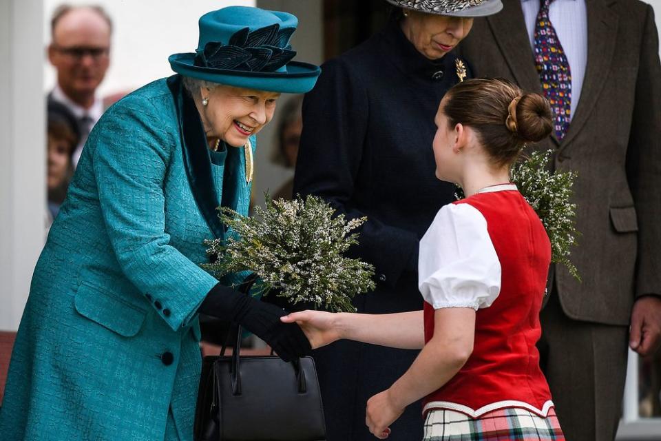 Queen Elizabeth II is presented with flowers as she attends the Annual Braemar Highland Gathering