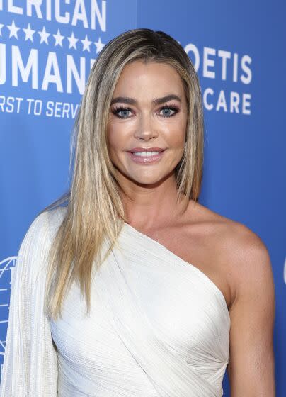 Denise Richards poses in a white dress at an event.