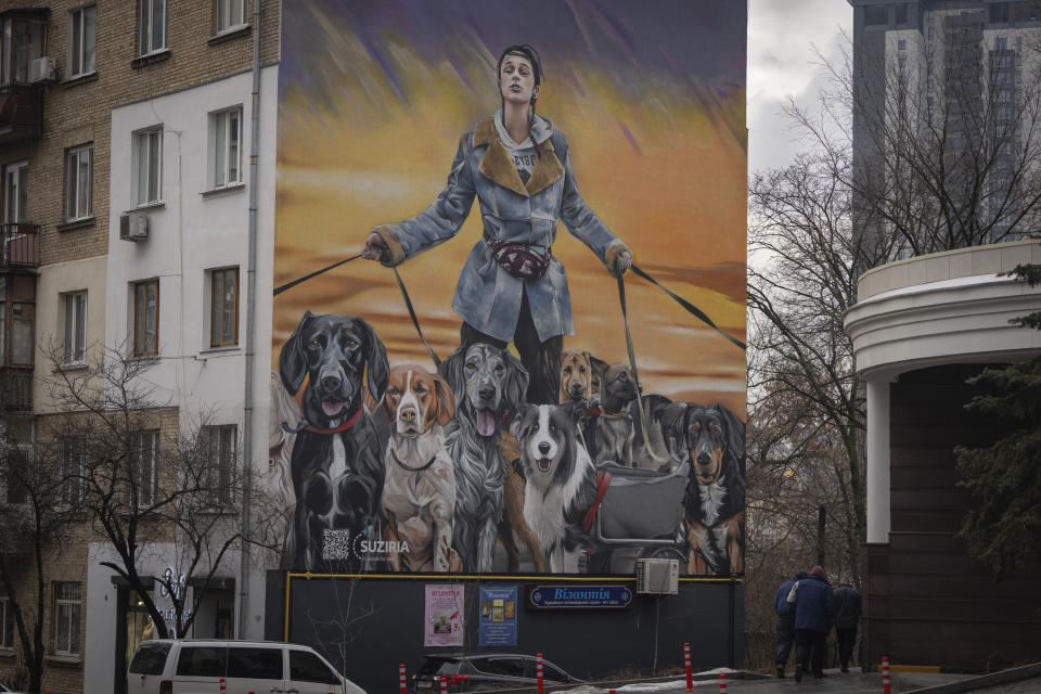 Este mural muestra a Anastasia Tykha, voluntaria en un zoo, con perros, en un edificio de apartamentos en Kiev, Ucrania, el 19 de enero de 2024. Tykha salvó a unos 30 perros durante los duros combates contra las fuerzas rusas en su ciudad natal, Irpin, cerca de Kiev, en marzo de 2022. (AP Foto/Efrem Lukatsky)
