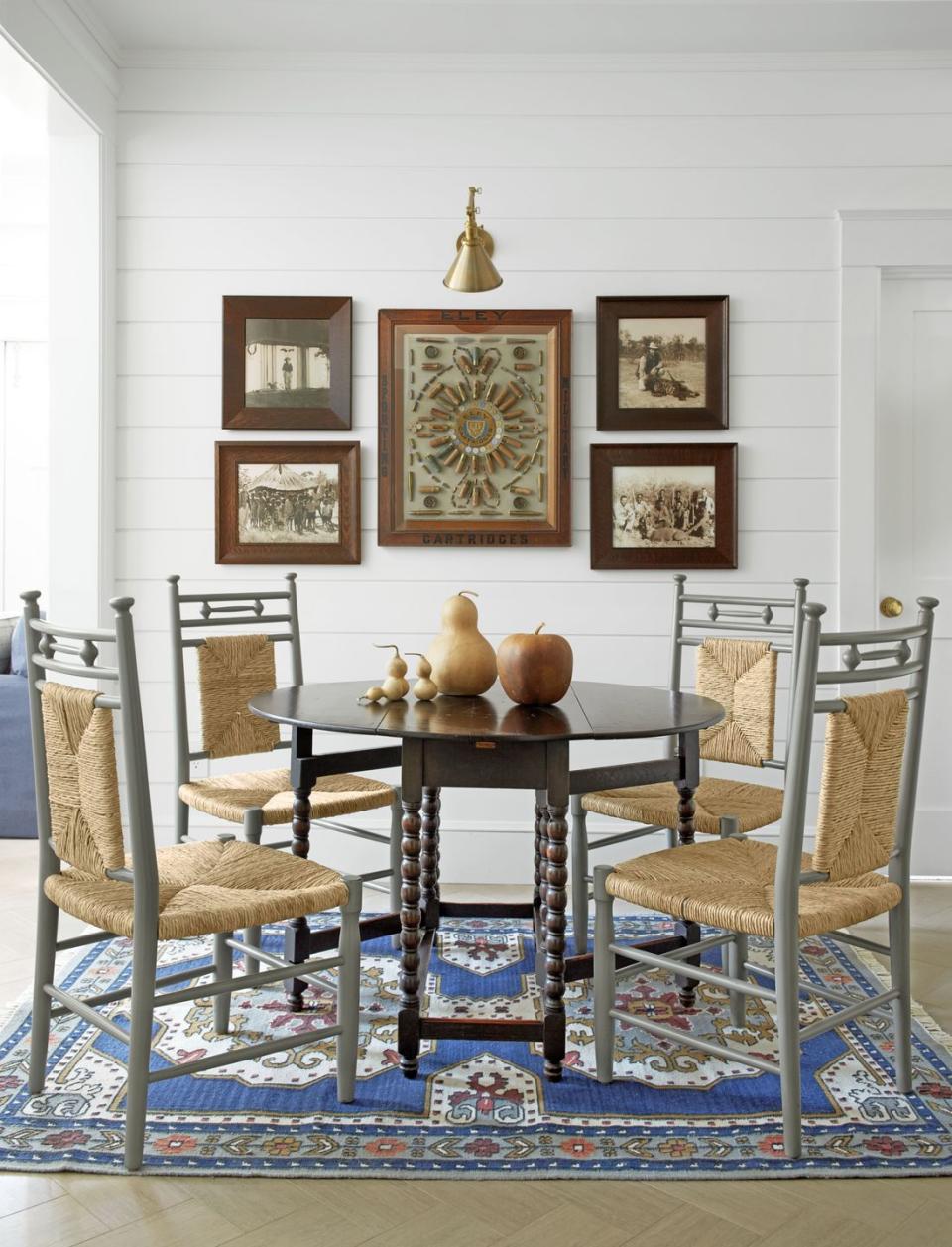 white dining room with a blue patterned rug and wood dining table with gray painted chairs