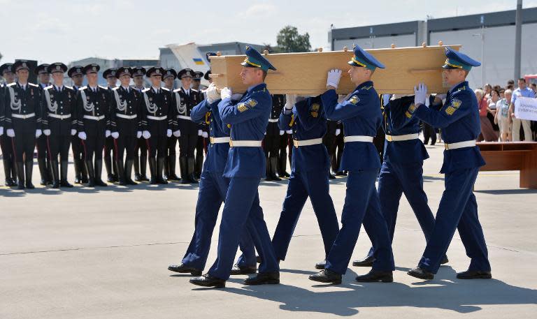 Ukrainian soldiers carry a coffin with the remains of a victim of the Malaysia Airlines flight MH17 crash during a ceremony in Kharkiv, on July 23, 2014