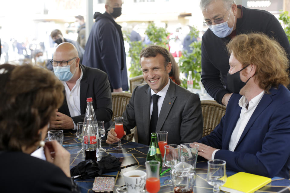 French President Emmanuel Macron shares a drink with shopkeepers during a visit to mark the reopening of cultural activities after closures during the Covid-19 pandemic, in Nevers, central France, Friday, May 21, 2021. (AP Photo/Thibault Camus, Pool)