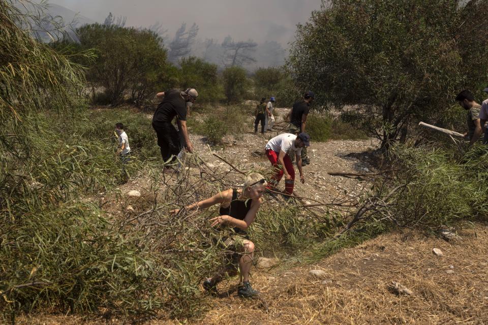 Volunteers take part at an operation against a wildfire in Vati village, on the Aegean Sea island of Rhodes, southeastern Greece, on Tuesday, July 25, 2023. A third successive heat wave in Greece pushed temperatures back above 40 degrees Celsius (104 degrees Fahrenheit) across parts of the country Tuesday following more nighttime evacuations from fires that have raged out of control for days. (AP Photo/Petros Giannakouris)