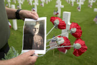 <p>Mark Shively, from Beaverton, Oregon, shows a photo of his grandfather, World War I Marine Corps Private Norman Alfred Roberts, as he leaves flowers at the grave of his grandfather’s unit commander Lt. Carleton Burr during Memorial Day weekend at the Aisne-Marne American Cemetery in Belleau, France, Saturday, May 26, 2018. Roberts, wounded during the Battle of Belleau Wood in June of 1918, made it home to America before the war ended. His unit commander Lt. Carleton Burr was killed in nearby Vierzy, France in July 1918. (Photo: Virginia Mayo/AP) </p>