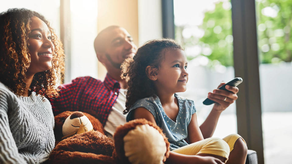 Shot of a happy young family of three watching tv from the sofa at home.