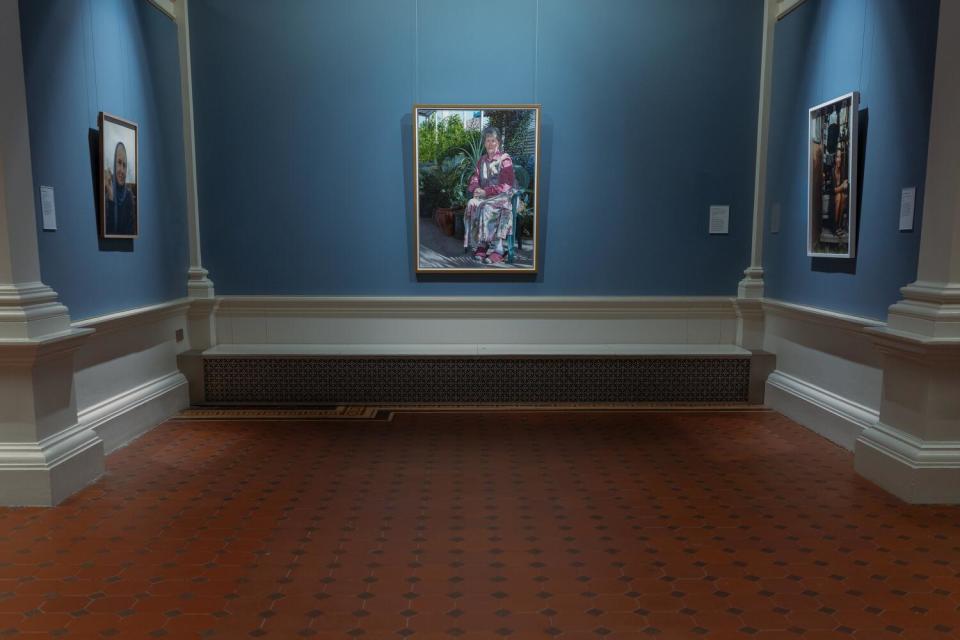 Paintings hang on each of three walls in a museum alcove.