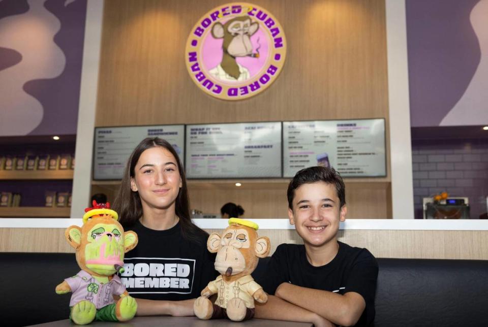 Nico Castellanos, de 13 años, derecha, y Ale, de 14, posan con los peluches que ayudaron a diseñar en el restaurante Bored Cuban en Miami.