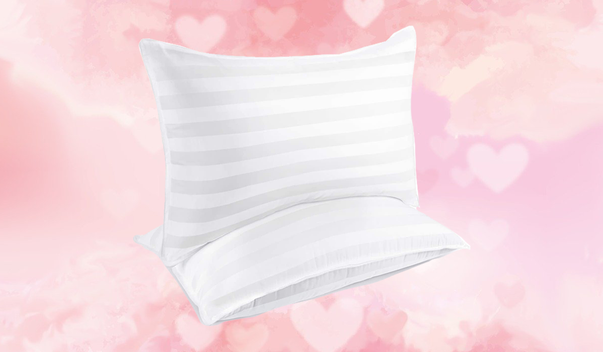 Two queen pillows on a pink background with floating hearts