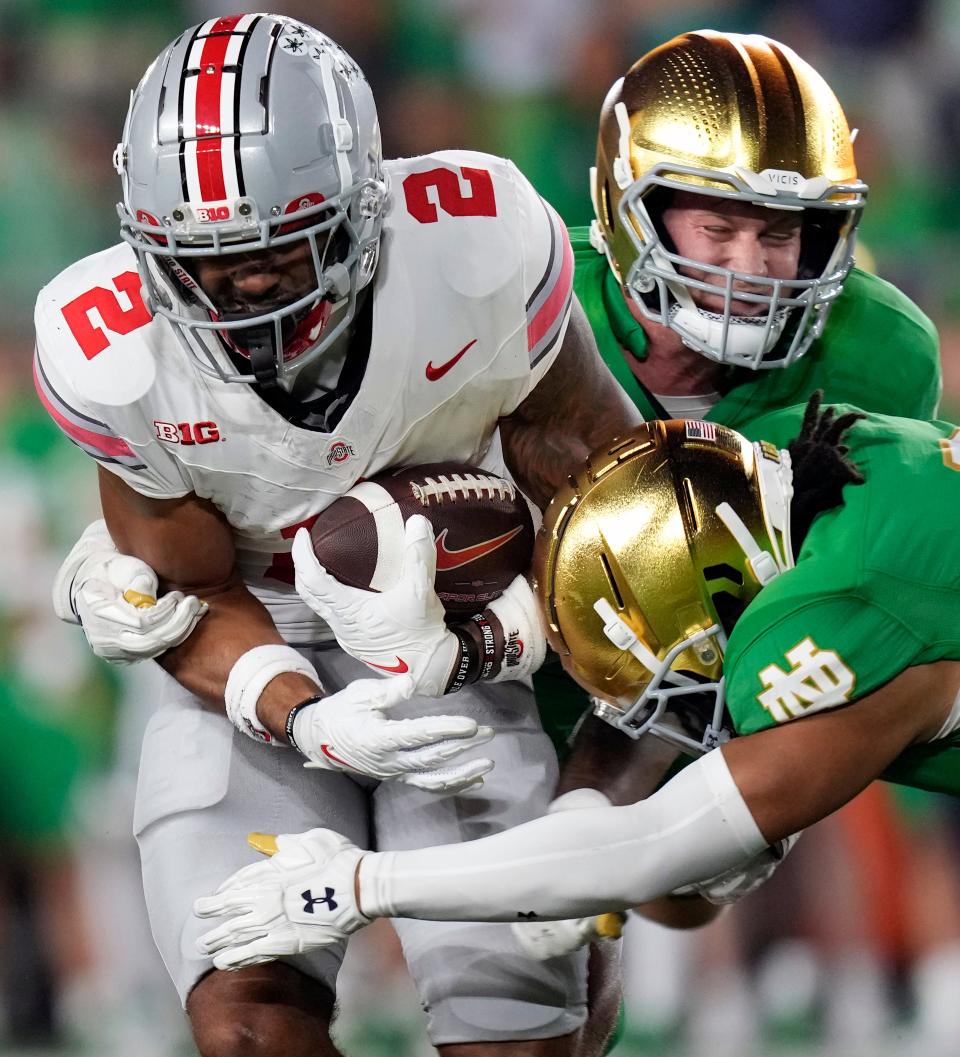 Ohio State receiver Emeka Egbuka makes a catch against Notre Dame's Cam Hart and JD Bertrand.