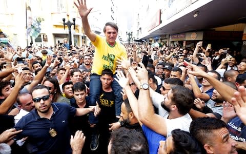 Jair Bolsonaro is taken on the shoulders of a supporter moments before being stabbed - Credit: Antonio Scorza