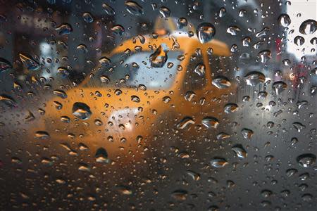 A taxi is pictured through the window of another taxi in the rain in Times Square in New York February 5, 2014. REUTERS/Carlo Allegri