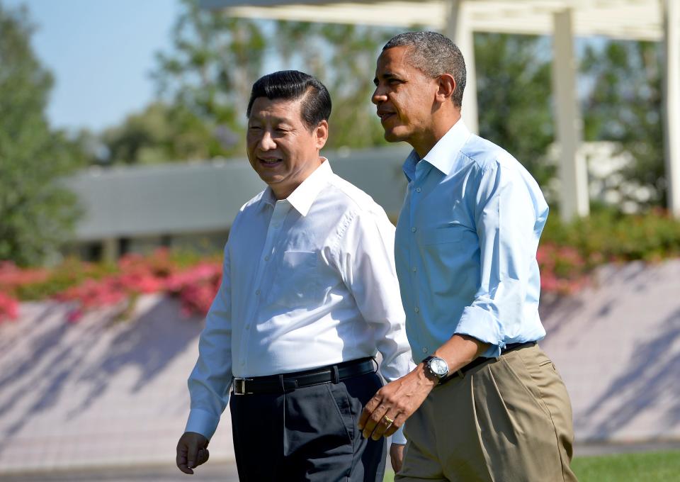 Obama and Xi walk side by side in a garden.