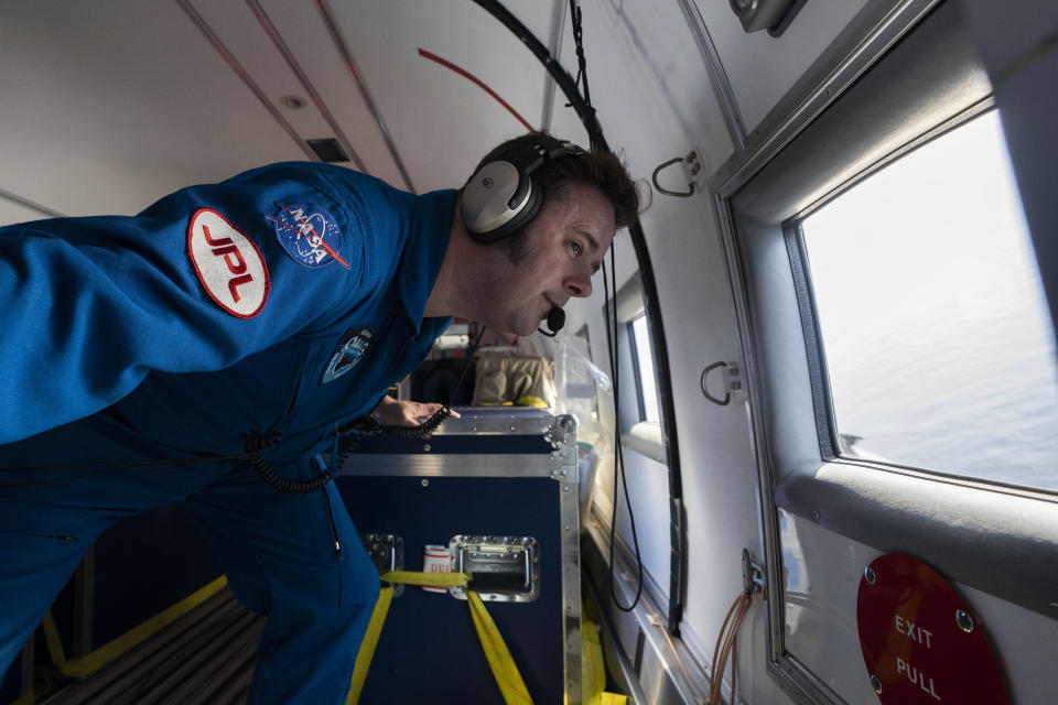 In this photo taken on Wednesday, Aug. 14, 2019, NASA scientist Josh Willis looks out of the window after dropping a probe from a plane as they fly above the Kangerlussuaq Glacier, eastern Greenland. Greenland has been melting faster in the last decade and this summer, it has seen two of the biggest melts on record since 2012. (AP Photo/Mstyslav Chernov)