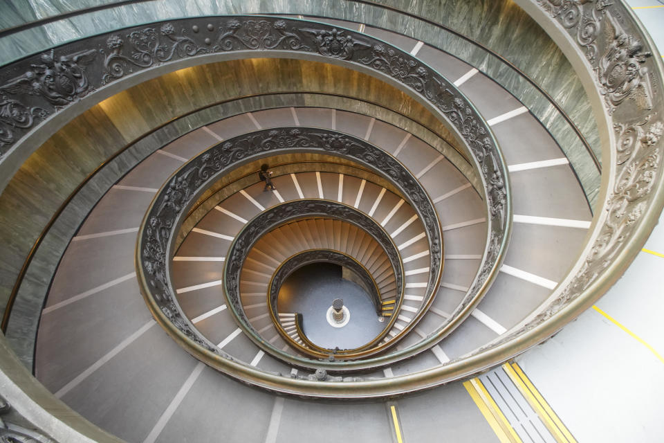 A visitor walks down a staircase, designed by architect Giuseppe Momo in 1932, as she leaves the Vatican Museums, at the Vatican, Monday, Feb. 1, 2021. The Vatican Museums reopened Monday to visitors after 88 days of shutdown following COVID-19 containment measures. (AP Photo/Andrew Medichini)