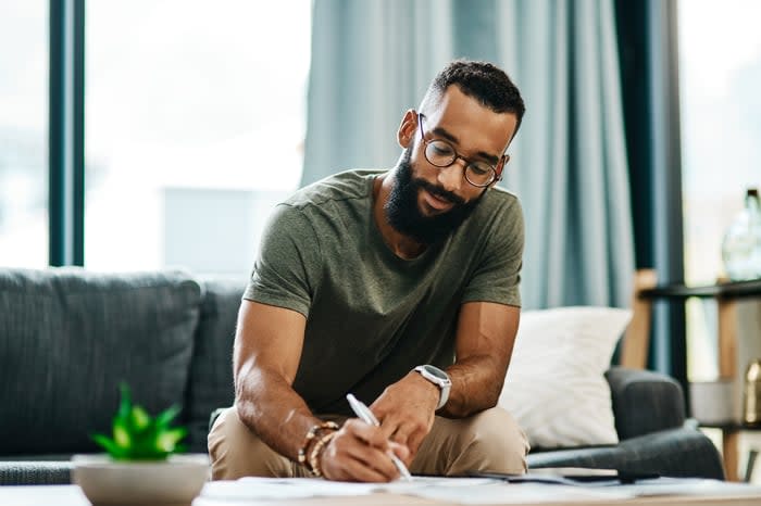 Person sitting on a couch looking at paperwork.