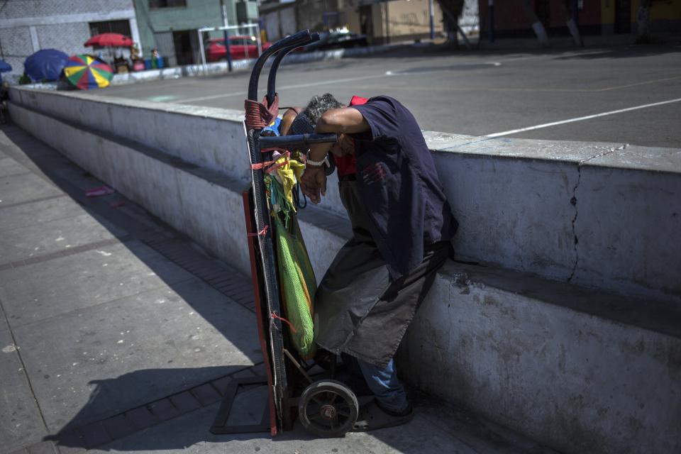 Un hombre se duerme sobre el carrito que usa para transportar mercaderías en un supermercado de Lima el 19 de marzo del 2020. El individuo no puede quedarse en su casa en plena pandemia del coronavirus porque si no trabaja no come. (AP Photo/Rodrigo Abd, File)