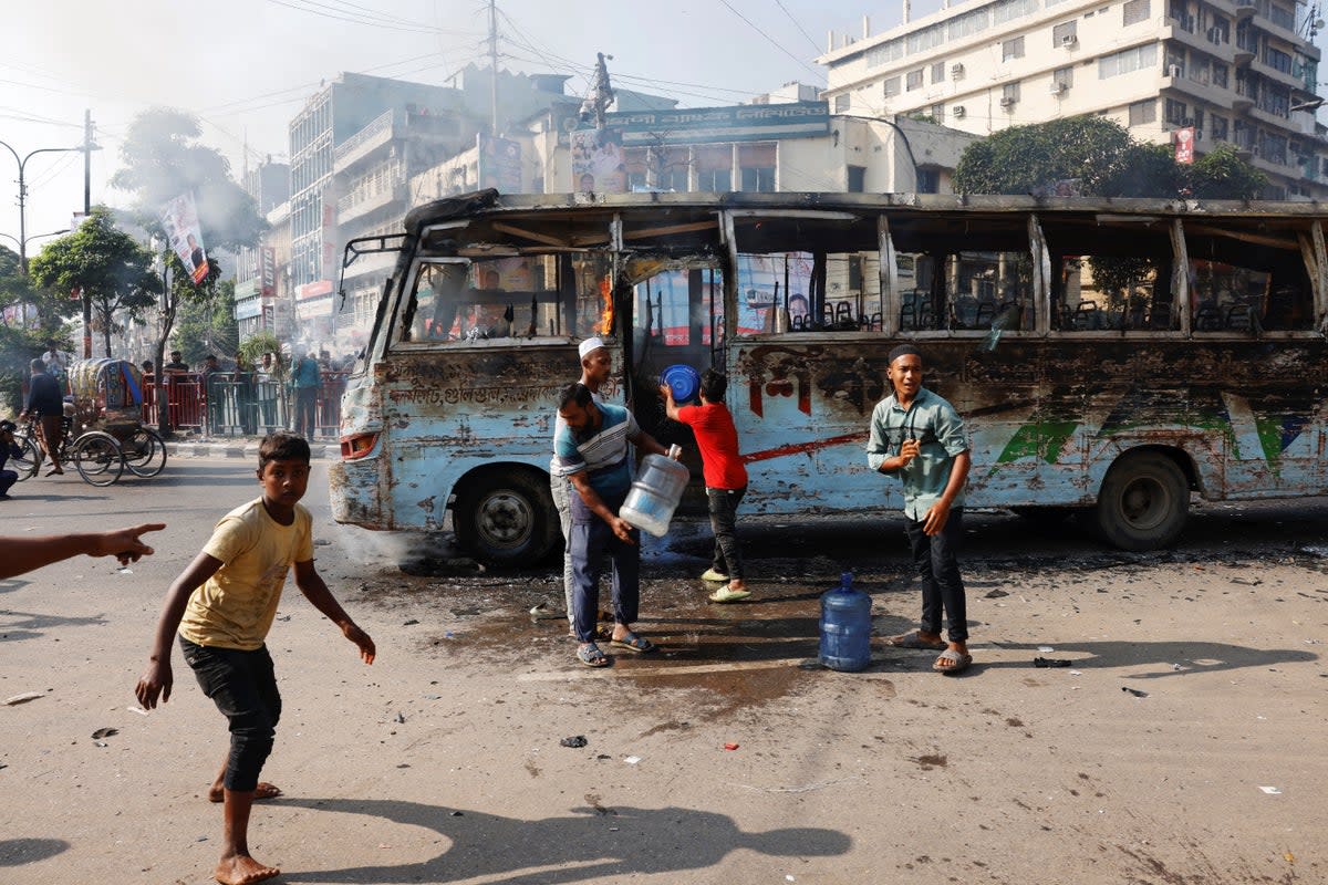 People try to douse the fire after a public bus was set on fire during a countrywide strike from dawn to dusk called by the Bangladesh Nationalist Party (BNP), protesting against alleged police attacks on their Saturday rally in Dhaka, Bangladesh (Reuters)